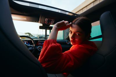 a woman sitting in a car with her hand on her head