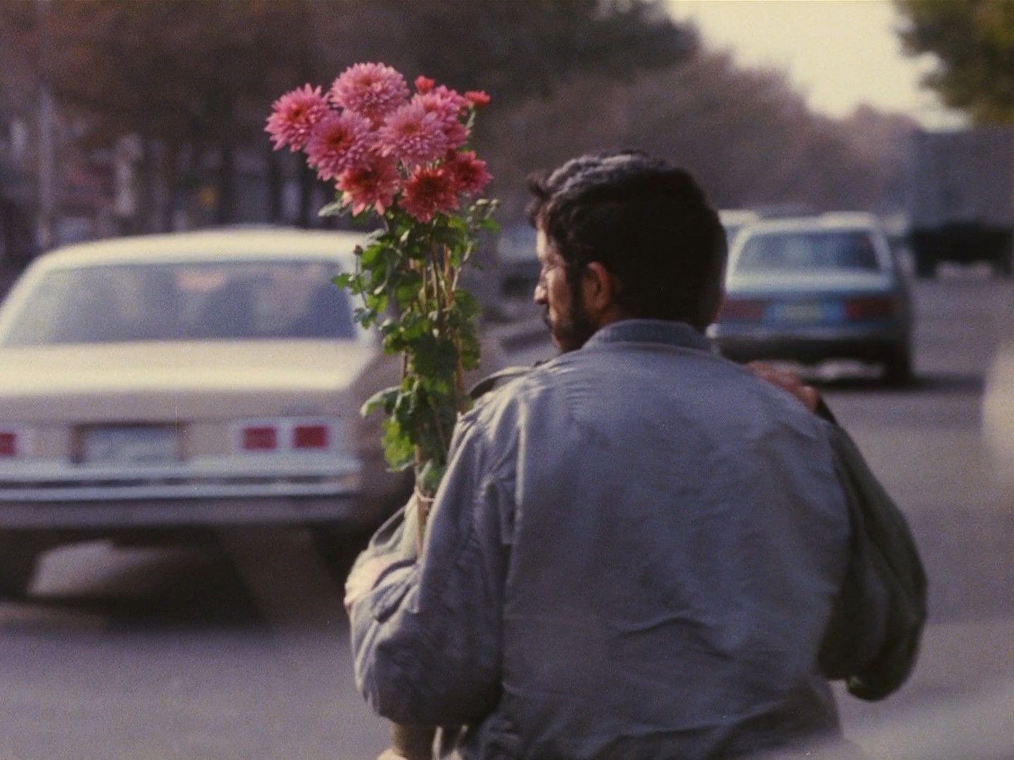 a man walking down the street with a flower in his hand