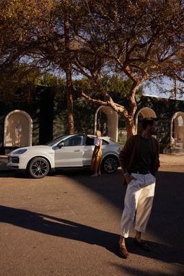 a man walking down a street next to a white car