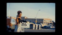 a woman walking down a street next to a traffic light