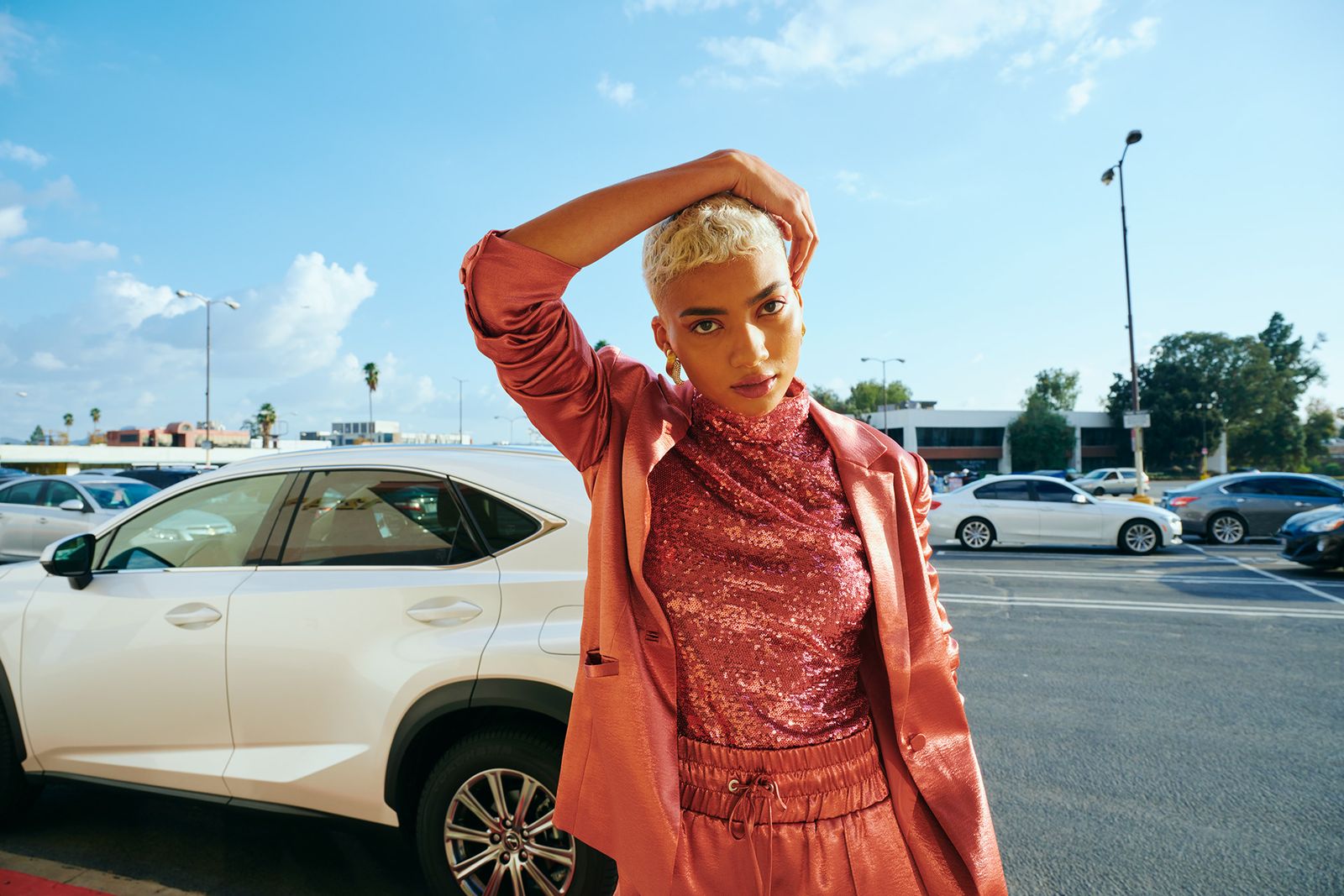 a woman standing next to a white car in a parking lot