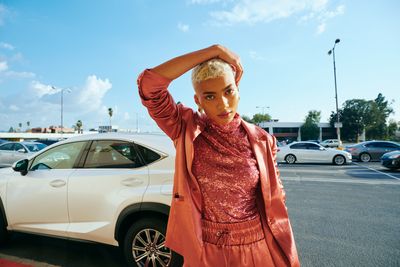 a woman standing next to a white car in a parking lot