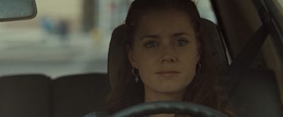 a woman sitting in a car with a steering wheel