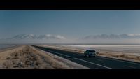 a car driving down a highway next to a large body of water