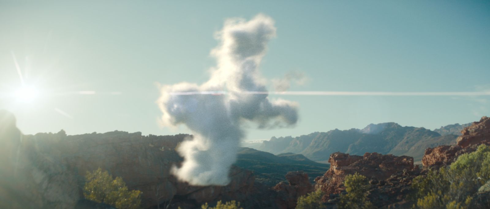 a cloud shaped like a cross on top of a mountain