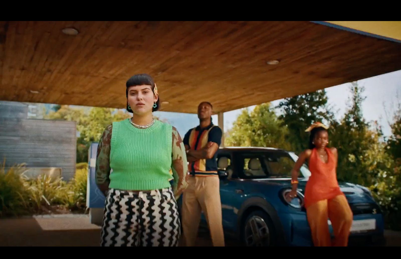 a woman standing in front of a blue car