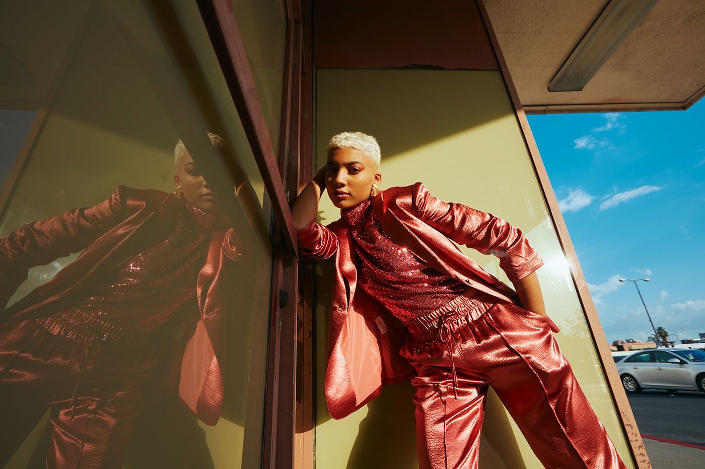 a woman in a red suit leaning against a wall