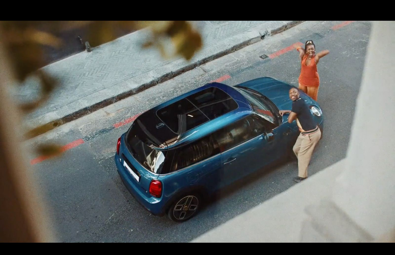 a man and woman standing next to a blue car