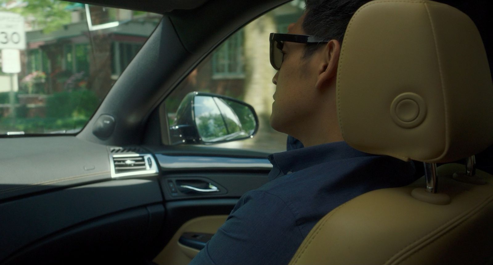 a man in a car wearing sunglasses and a blue shirt