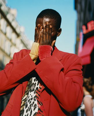 a man in a red coat covers his face with his hands