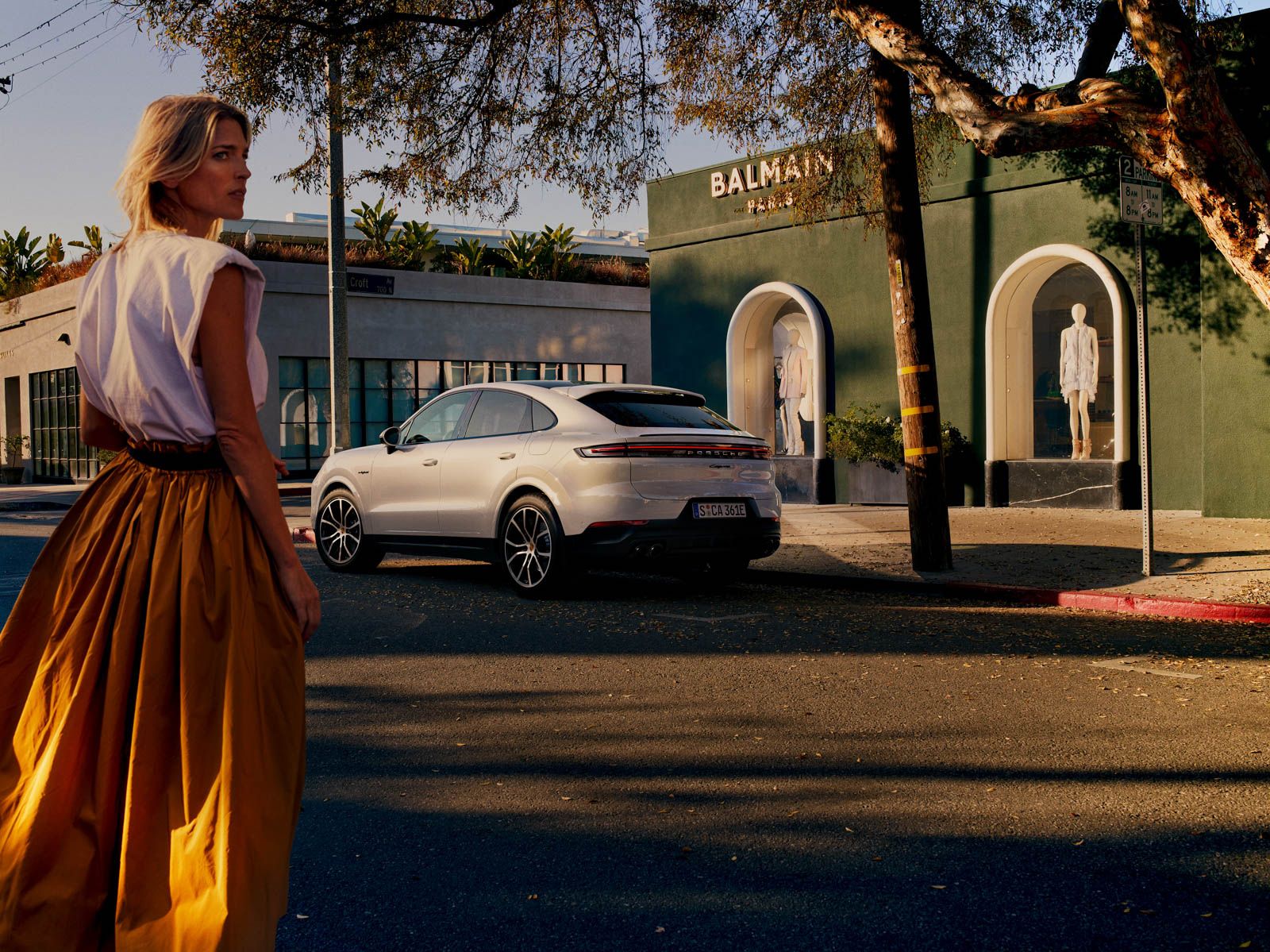 a woman walking across a street next to a white car