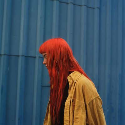 a woman with long red hair standing in front of a blue building