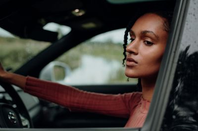 a woman driving a car with her hand on the steering wheel