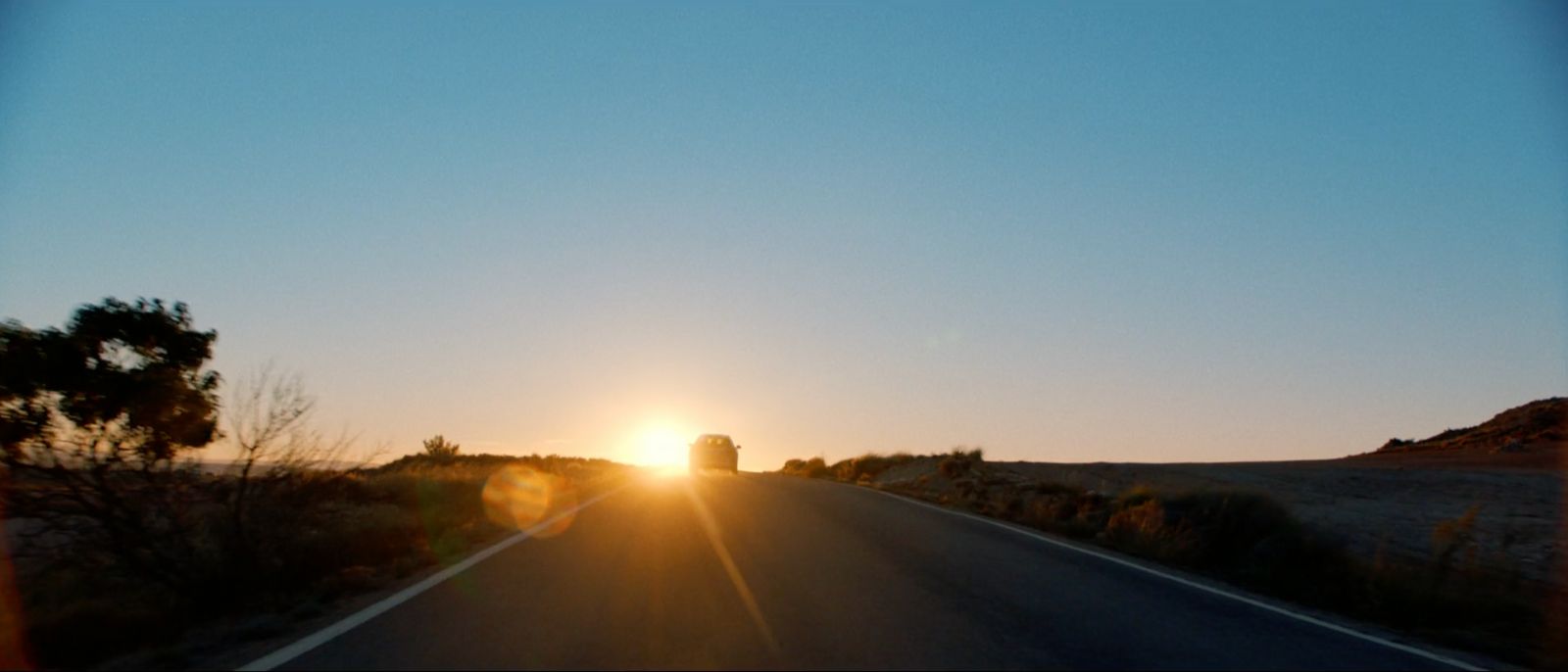 a car driving down a road at sunset