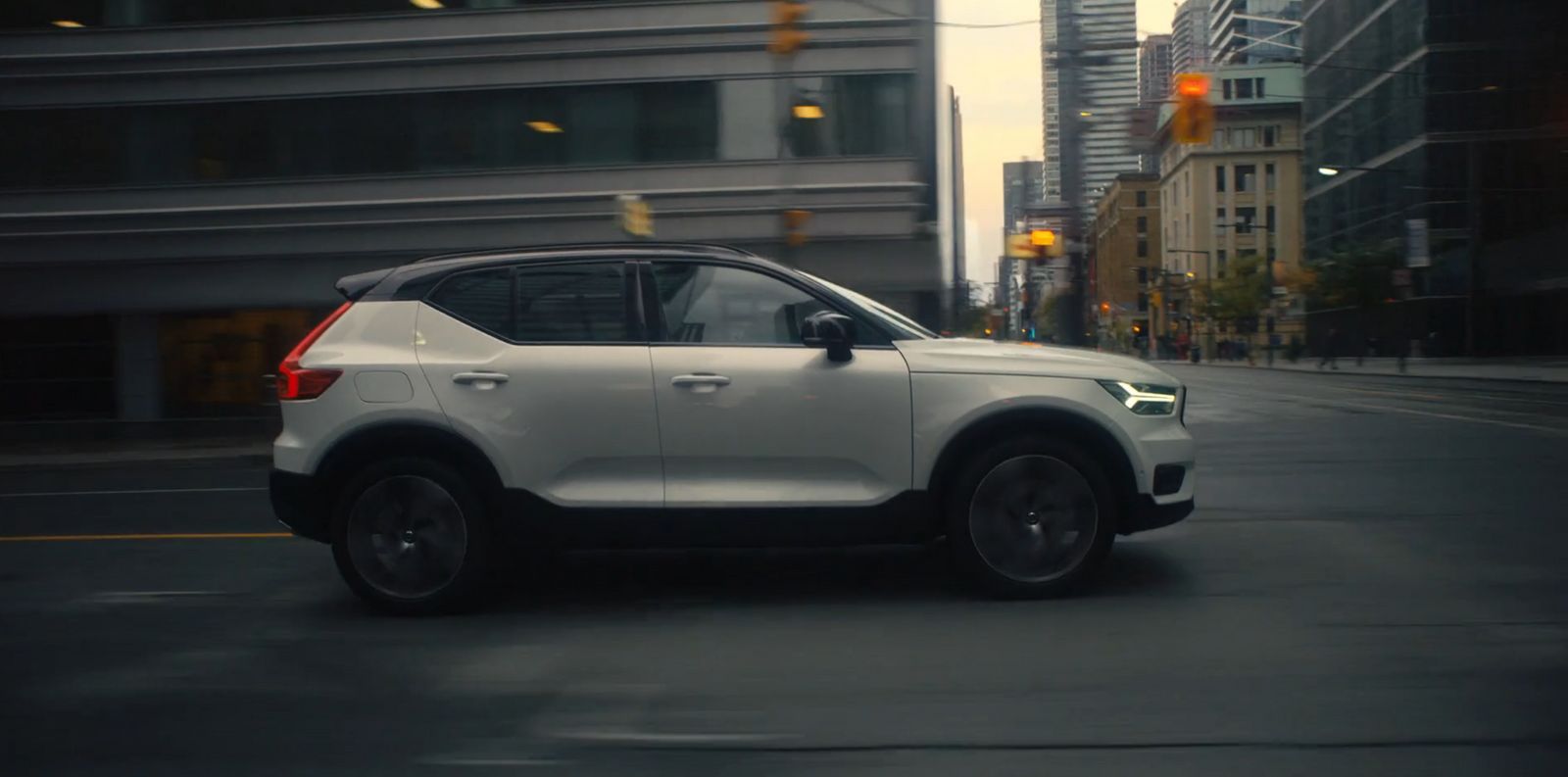 a white car driving down a street next to tall buildings