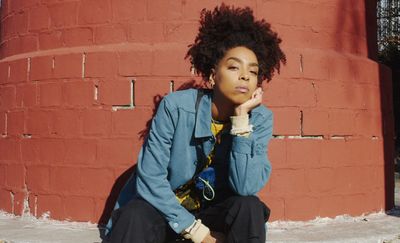 a woman sitting on the ground next to a brick wall