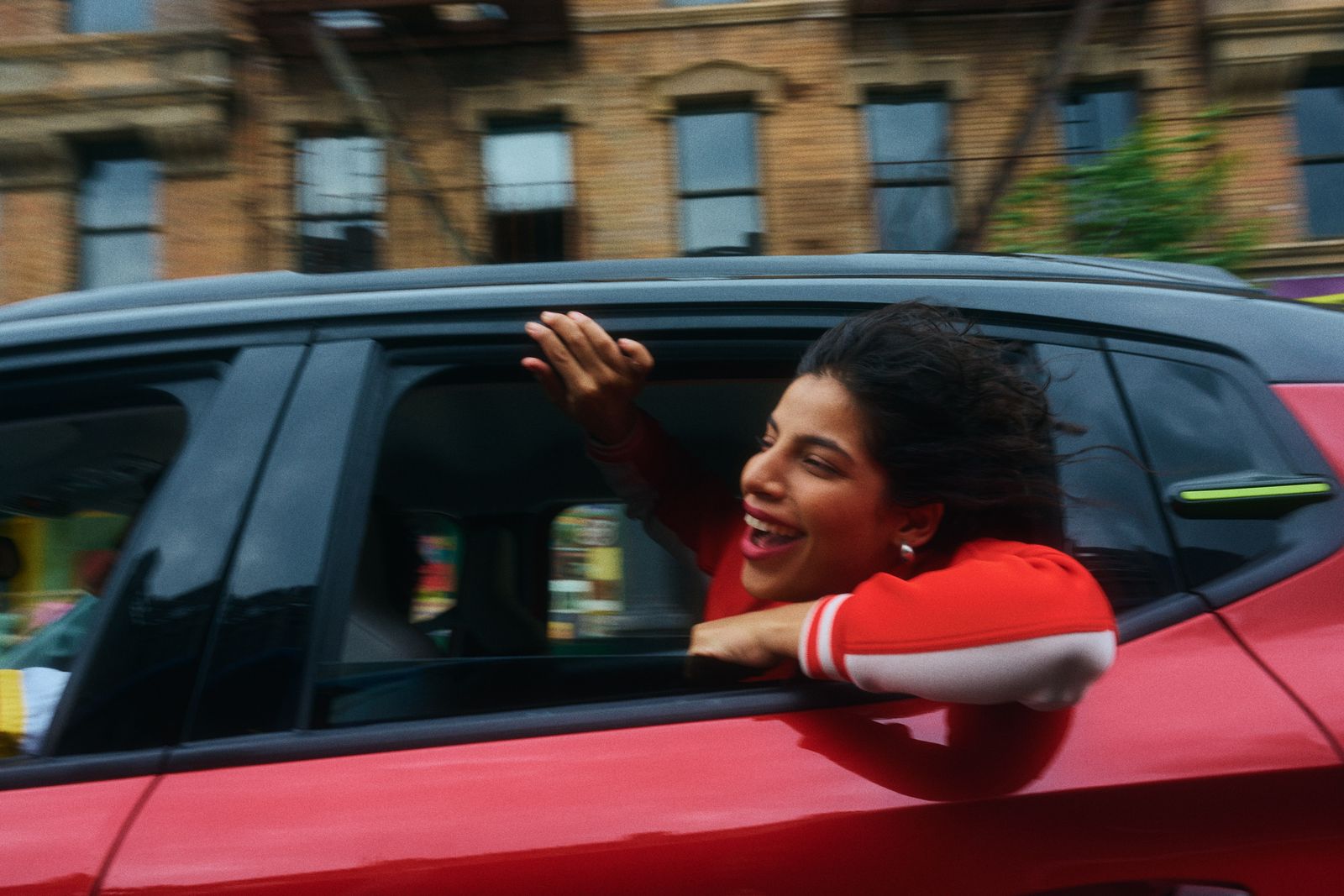 a woman in a red car waving out the window