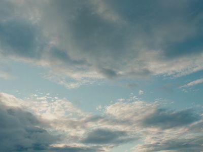 a plane flying through a cloudy blue sky