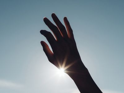 a person's hand reaching up into the sky