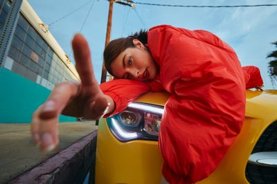 a woman leaning on the hood of a yellow sports car