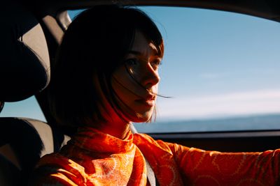 a woman sitting in a car with a scarf around her neck