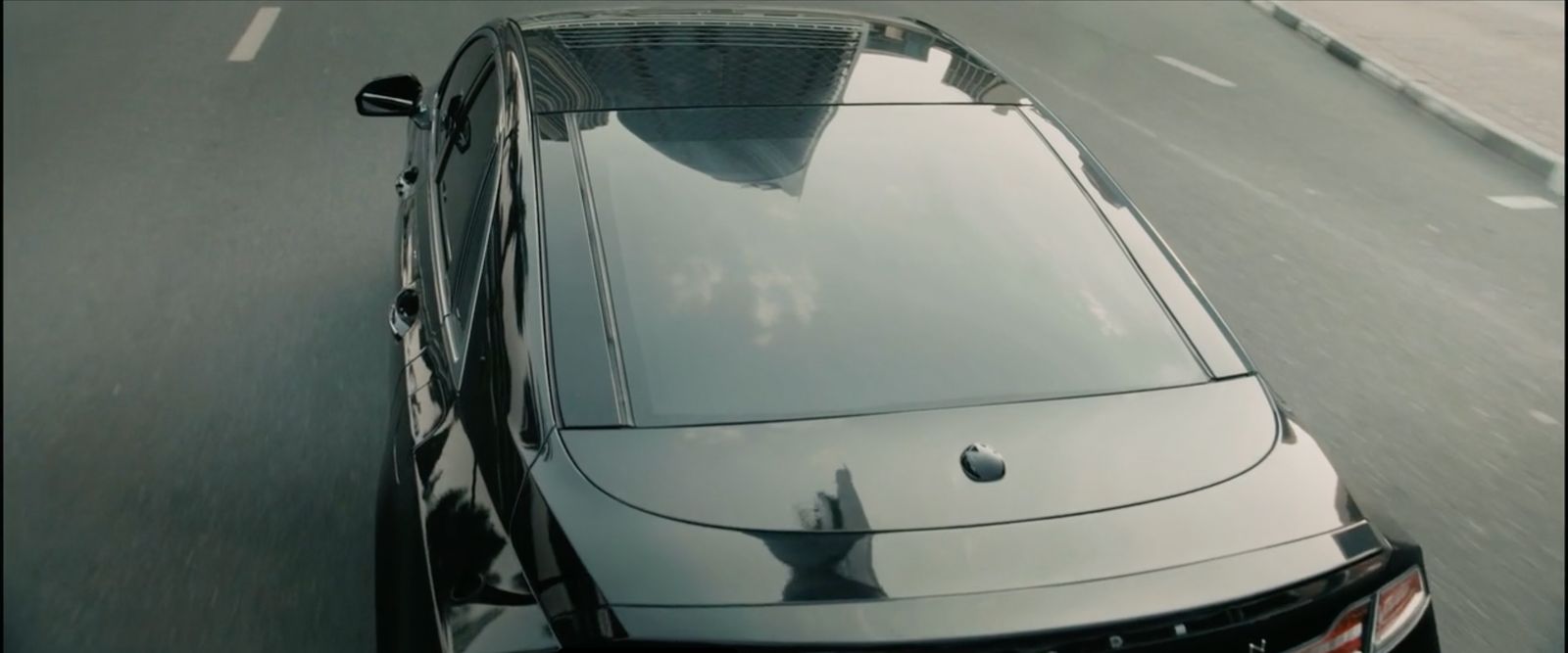 a black car driving down a street next to a tall building