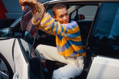 a boy sitting in a car with his hand up