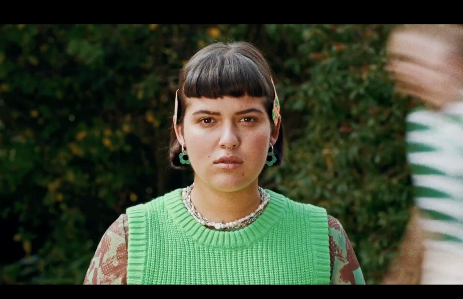 a woman wearing a green sweater and earrings