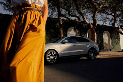 a woman in a yellow dress standing next to a white car