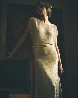 a woman in a gold dress standing in front of a mirror