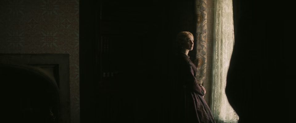 a woman standing in front of a window in a dark room