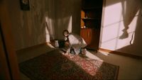 a person kneeling down on a rug in a room