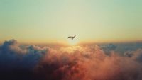 a plane flying over the clouds at sunset