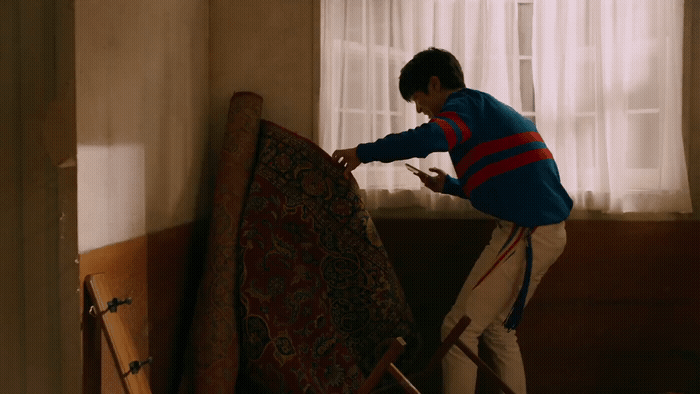 a man in a blue sweater is working on a rug