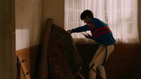 a man in a blue sweater is working on a rug
