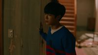 a young boy standing in a hallway next to a door