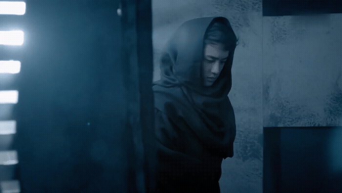 a man in a hoodie standing in a dark room