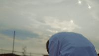 a man looking up at a kite flying in the sky