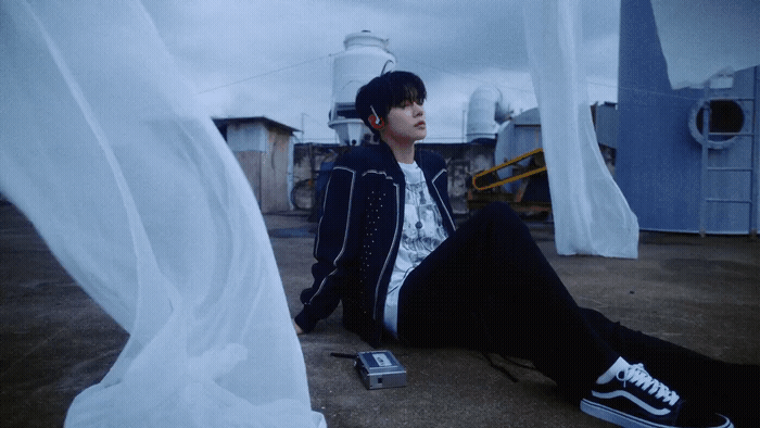 a young man sitting on the ground with a cell phone