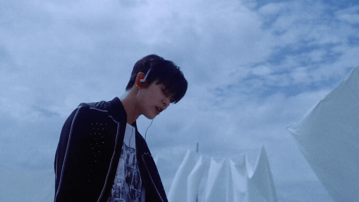 a man with earphones standing in front of a building