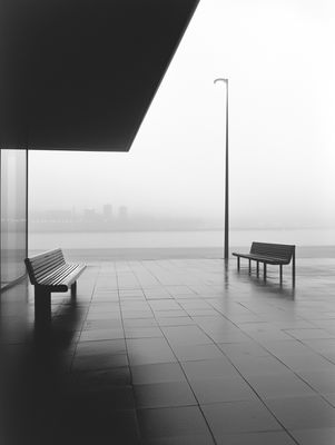 a black and white photo of a bench and street light