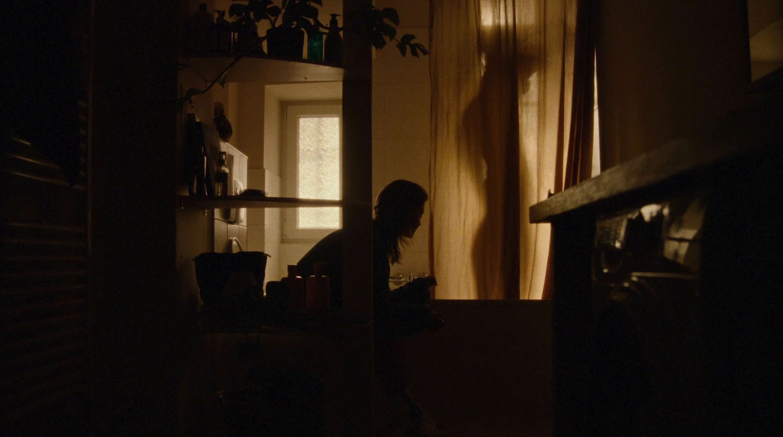 a person sitting in a dark room with a window