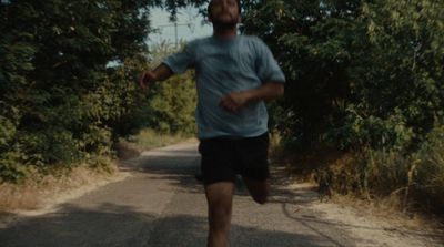 a man running down a road next to a forest