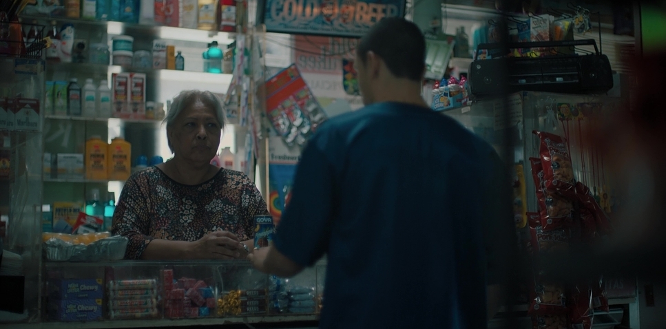 a man standing in front of a store counter talking to a woman