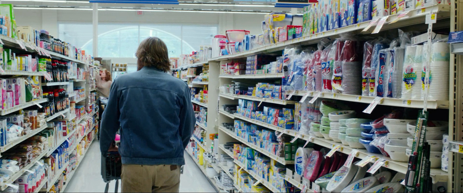 a man is walking down a aisle in a store