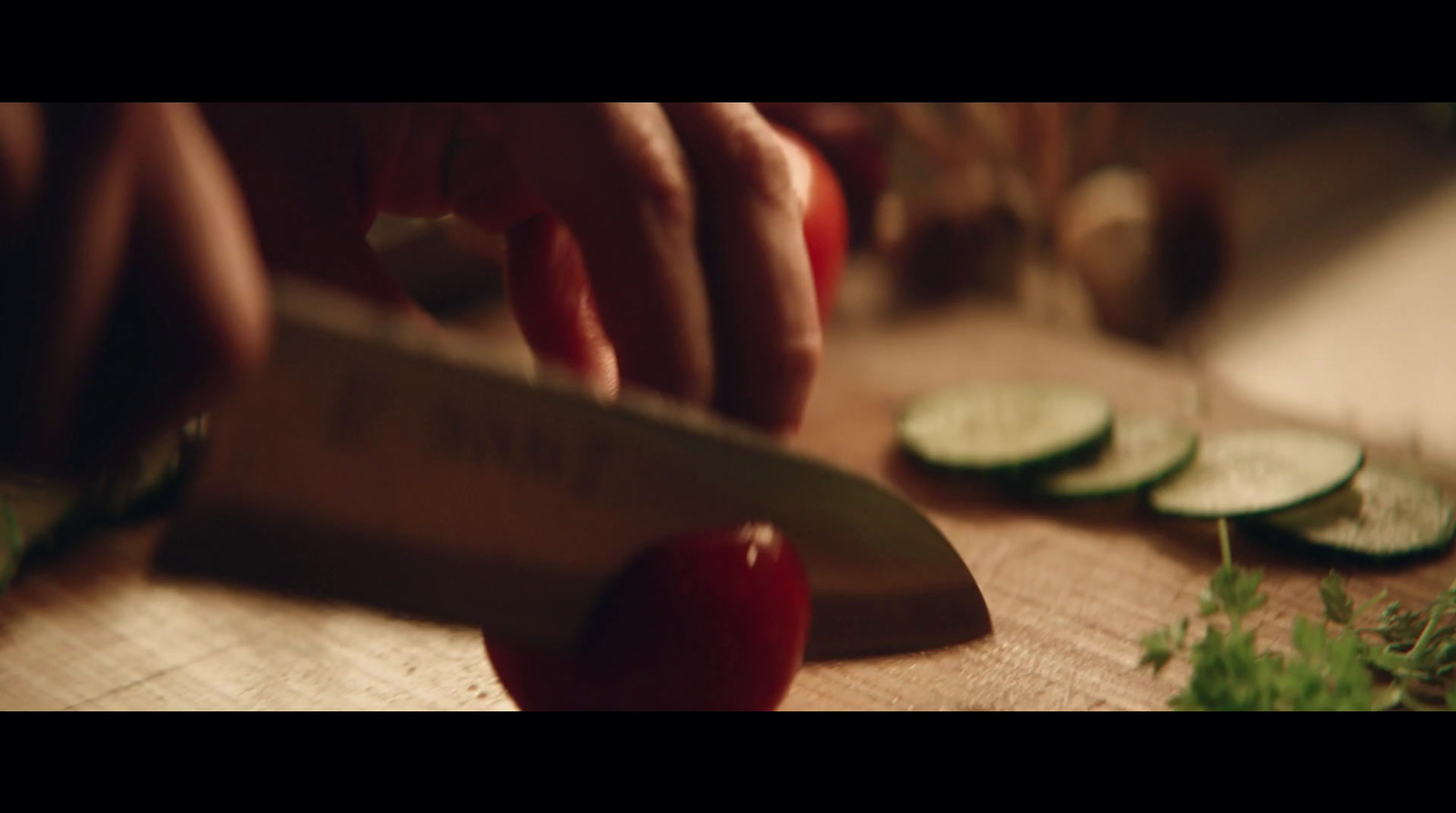 a person cutting up a cucumber on a cutting board