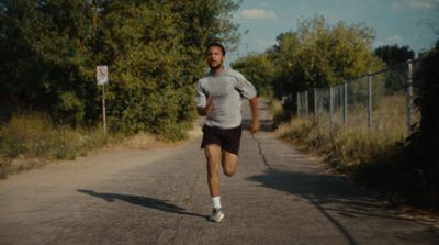 a man running down a road with trees in the background