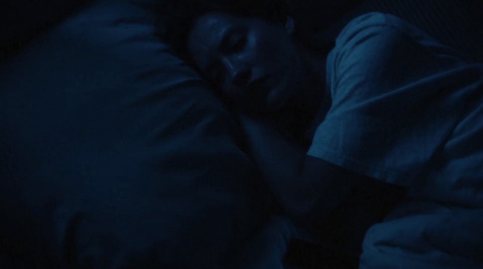 a person sleeping in a bed in the dark