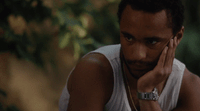 a man in a tank top holding his hand to his face