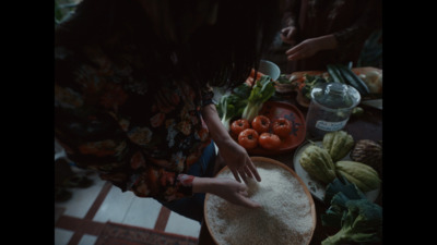 a woman standing over a table filled with lots of food